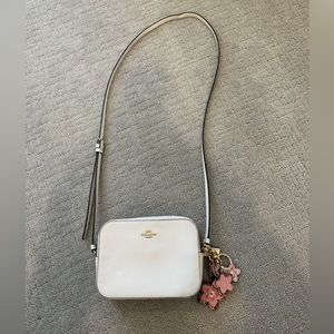 Coach crème crossbody camera bag with flower Coach keychain.